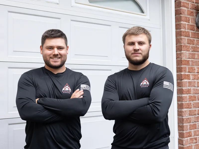 Two Apex Garage Doors technicians standing in front of a white residential garage door