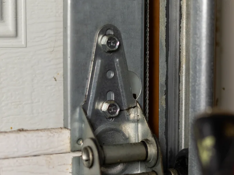 Close-up of a steel garage door hinge and roller stem seated in the vertical track
