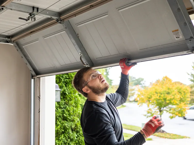 Apex Garage Doors technician servicing a raised sectional door inside a residential garage