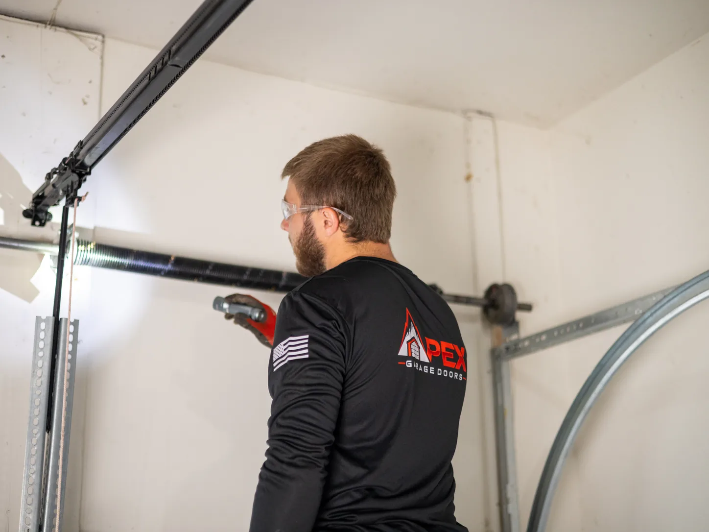 Apex Garage Doors technician inspecting the horizontal track and opener rail inside a garage