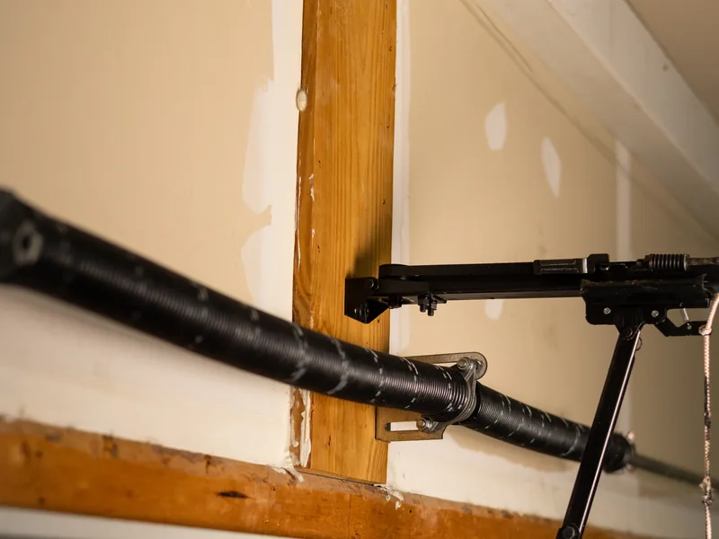 Torsion spring assembly and center bracket above a garage door header inside a home garage