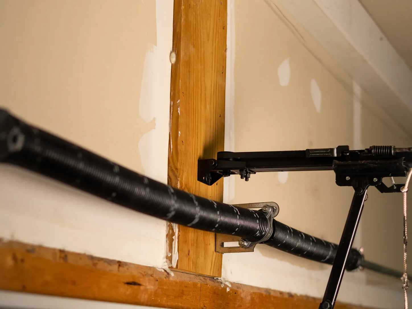 Torsion spring assembly and center bracket above a garage door header inside a home garage