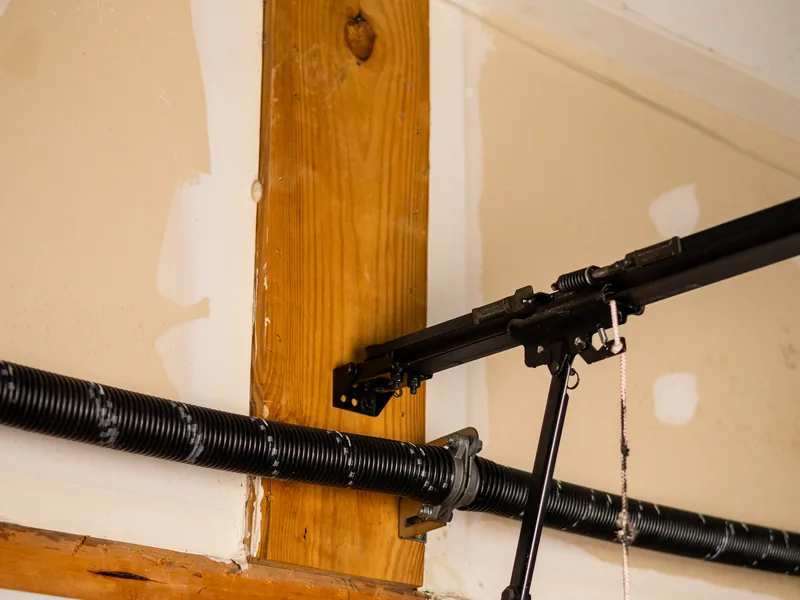 Torsion spring and opener rail mounted above a residential garage door with window panels